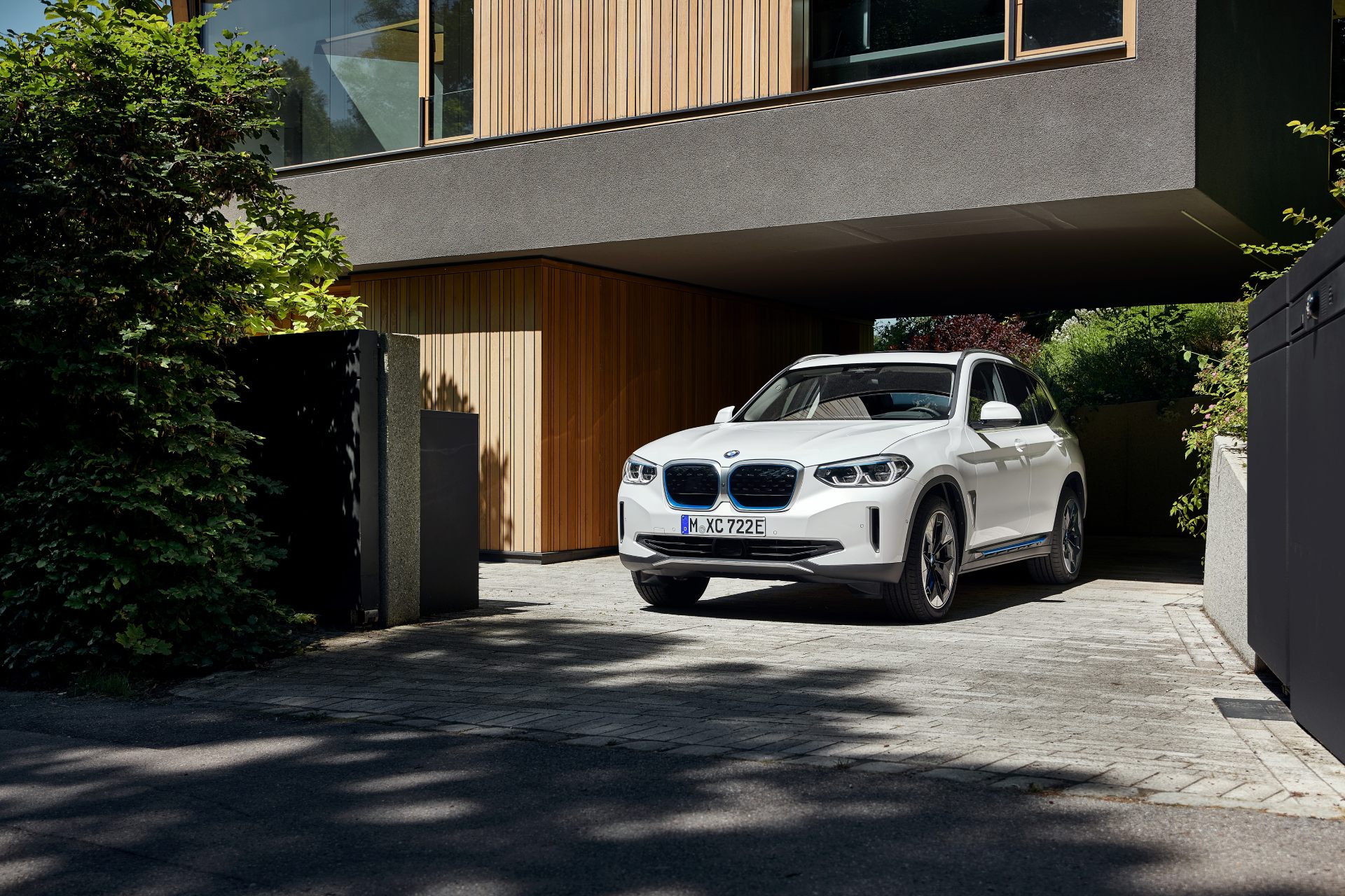 BMW iX3 parkerad vid hus